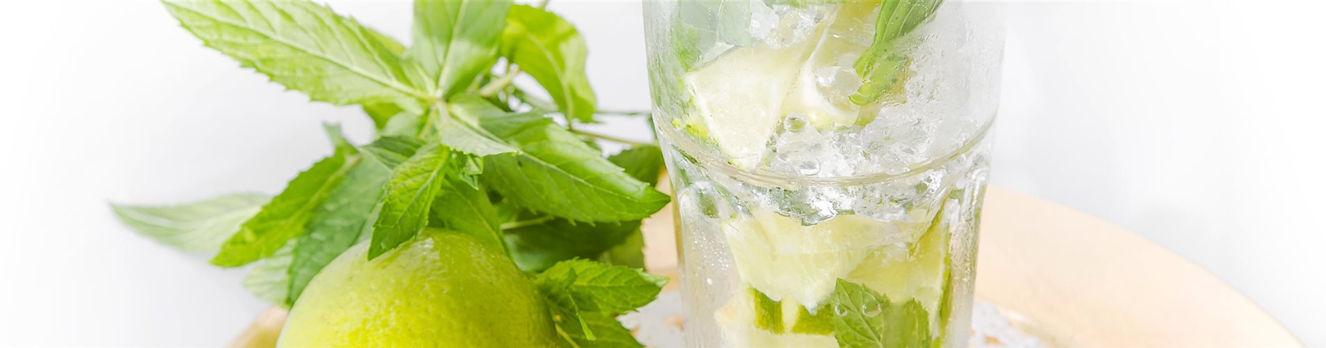 Ein Glas Mojito, links daneben eine Zitrone