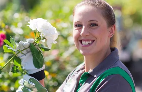 bellaflora Mitarbeiterin grinst in die Kamera mit Blume in der Hand