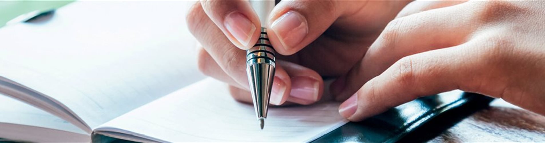 Person, die Notzien in ein kleines Heft schreibt